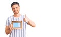 Handsome young man with bear holding empty frame smiling happy and positive, thumb up doing excellent and approval sign Royalty Free Stock Photo