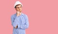 Handsome young man with bear wearing architect hardhat serious face thinking about question with hand on chin, thoughtful about Royalty Free Stock Photo