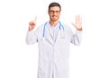 Handsome young man with bear wearing doctor uniform showing and pointing up with fingers number six while smiling confident and Royalty Free Stock Photo