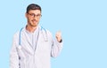 Handsome young man with bear wearing doctor uniform smiling with happy face looking and pointing to the side with thumb up Royalty Free Stock Photo