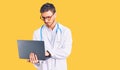 Handsome young man with bear wearing doctor uniform working using computer laptop thinking attitude and sober expression looking Royalty Free Stock Photo