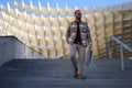 Handsome young man with beard comes down stairs with shopping bag in hand. Man is dressed casually and in modern clothes. Shopping