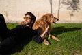 Handsome young man with beard and glasses lying on the grass sunbathing with his brown golden retriever dog. Concept pets, animals Royalty Free Stock Photo