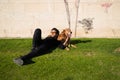 Handsome young man with beard and glasses lying on the grass sunbathing with his brown golden retriever dog. Concept pets, animals Royalty Free Stock Photo