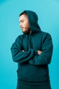 handsome young man with a beard in a green tracksuit looking to the side on a blue background. isolated