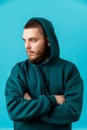 handsome young man with a beard in a green tracksuit looking to the side on a blue background. isolated