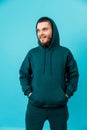 handsome young man with a beard in a green tracksuit looking to the side on a blue background. isolated