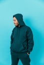 handsome young man with a beard in a green tracksuit looking to the side on a blue background. isolated