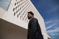 Handsome young man with beard, sculpted body, walking through the park before arriving at the building where he works as office Royalty Free Stock Photo