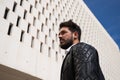 Handsome young man with beard, sculpted body, walking through the park before arriving at the building where he works as office Royalty Free Stock Photo