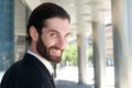 Handsome young man with beard smiling outside