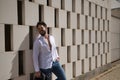 Handsome young man with beard, sunglasses and open white shirt, leaning against a wall of white stone blocks, smiling in sexy Royalty Free Stock Photo