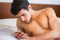Handsome young man in bed typing on cell phone Royalty Free Stock Photo
