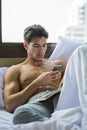 Handsome young man in bed typing on cell phone Royalty Free Stock Photo