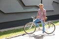 Handsome young man with bicycle near gray wall outdoors