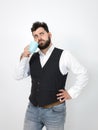 Handsome, young man with black beard posing with turquoise coffee cup or tea cup in front of white background