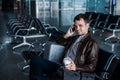 Handsome young man with black hair working, sitting on a chair things at the airport waiting for his flight Royalty Free Stock Photo