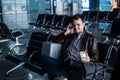 Handsome young man with black hair working, sitting on a chair things at the airport waiting for his flight Royalty Free Stock Photo