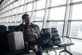 Handsome young man with black hair working, sitting on a chair things at the airport waiting for his flight Royalty Free Stock Photo
