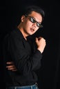 Handsome young man in black shirt keeping arms crossed wear glasses on black background , Asia Portrait Royalty Free Stock Photo