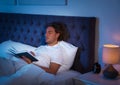 Handsome young man book in dark room at night. Bedtime Royalty Free Stock Photo