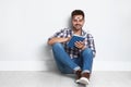 Handsome young man  book on wooden floor near light wall Royalty Free Stock Photo