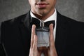 Handsome young man with bottle of perfume on grey stone background Royalty Free Stock Photo