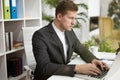 Handsome young man in business suit working in his laptop at his working place in office looking concentrated. multitasking, work Royalty Free Stock Photo