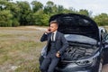 Handsome young man calling for assistance with his car broken down by the roadside. Royalty Free Stock Photo