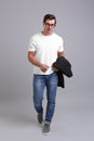 Handsome young man in casual clothes with jacket and glasses on grey background Royalty Free Stock Photo