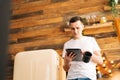 Handsome young man in casual clothes holding digital tablet and drinking coffee Royalty Free Stock Photo