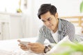 Handsome young man in casual clothes lying on the bed and playing mobile phone games, with excited emotions and expressions