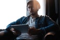 Handsome young man in casual clothes using a digital tablet and headphones and smiling while sitting on the chair. Royalty Free Stock Photo