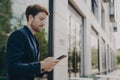 Handsome young man chatting and browsing web on his phone while standing outdoors Royalty Free Stock Photo