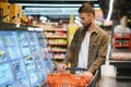 Handsome young man check the fridges for frozen food in the supermarket. Royalty Free Stock Photo