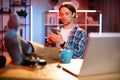 Handsome young man in checkered shirt put his feet on table with modern smartphone in hands. Royalty Free Stock Photo