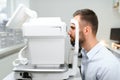 Handsome young man is checking the eye vision in modern ophthalmology clinic. Patient in ophthalmology clinic