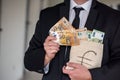 handsome young man in a classic suit with a tie holds in his hands a bag of euros. Royalty Free Stock Photo