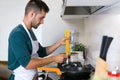 Handsome young man cooking pasta in the kitchen at home Royalty Free Stock Photo