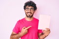 Handsome young man with curly hair and bear reading a  book smiling happy pointing with hand and finger Royalty Free Stock Photo