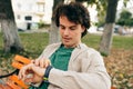 Handsome young man with curly hair, looking to the watch, sitting on the bench while wainting his girlfiriend on the city street Royalty Free Stock Photo