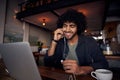 Handsome young man with curly hair watching videos on laptop with earphones in cafe Royalty Free Stock Photo