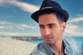 Handsome young, man in denim shirt and fedora hat sitting at beach Royalty Free Stock Photo