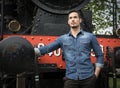 Handsome young man in denim shirt in front of old train Royalty Free Stock Photo