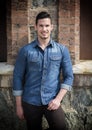 Handsome young man with denim shirt standing outdoors, smiling Royalty Free Stock Photo