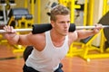 Handsome young man doing squats in gym