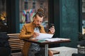 Attractive hipster reading papers in urban cafe Royalty Free Stock Photo