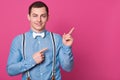 Handsome young man dresses blue shirt, points aside with his index fingeres. Good looking male with bow tie and suspenders. Model Royalty Free Stock Photo