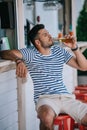 handsome young man drinking beer from glass bottle while sitting at beach Royalty Free Stock Photo