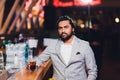 Handsome young man drinking cocktail at bar counter, wearing business suit. Royalty Free Stock Photo